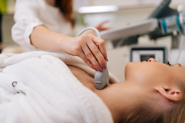 Closeup of beautiful woman examine thyroid gland with ultrasound probe in medical clinic. Close-up...