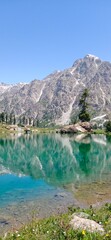 Naklejka na ściany i meble Stunning Reflection of Rocky Mountains in Crystal Clear Waters of Rainbow Lake with Lush Greenery, Pakistan