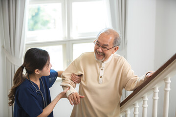 Young asian female nurse care giver helping asian senior old man in living area of nursing home...