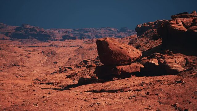 A striking image of a colossal rock, standing tall amidst the expansive red stone canyon desert.