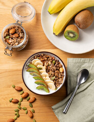 Muesli with yogurt, banana and kiwi on a wooden table.