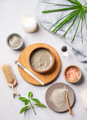 Organic cosmetic with blue clay, sea salt,  brush, candle and palm leaf on a light background.