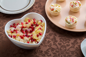 Fototapeta na wymiar on the table there is a salad in tartlets and a salad with pomegranate in a heart-shaped plate