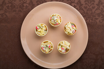 on the table is a salad in tartlets in a beige plate on a brown tablecloth. Horizontal photo