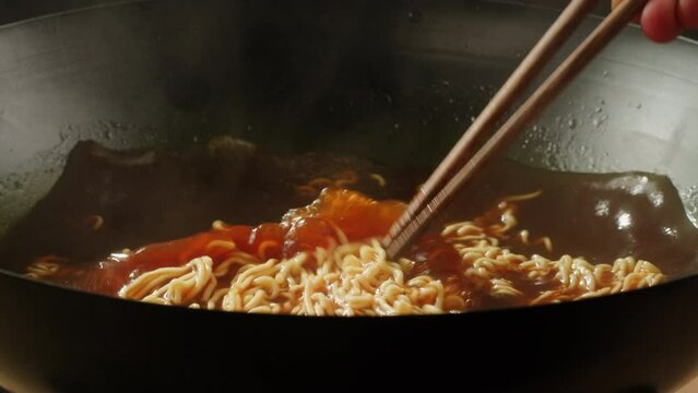 Cooking instant noodles in boiling water with spices close-up. Asian fast food. Instant noodles, or instant ramen, is a type of food consisting of noodles sold in a precooked and dried block with