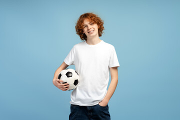 Portrait of smiling teenage boy holding ball playing football isolated