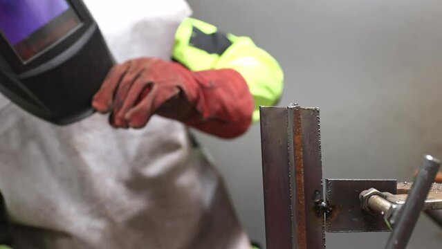 Welder man cleaning the metal part by a metallic brush after welding process, industrial concept