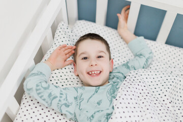 Happy caucasian schoolboy in bed