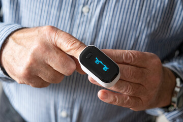 A pulse oximeter on an elderly man's finger.