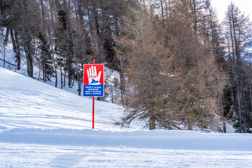 Sign warning in Italian, German, French and English about danger of avalanches in the mountains,...