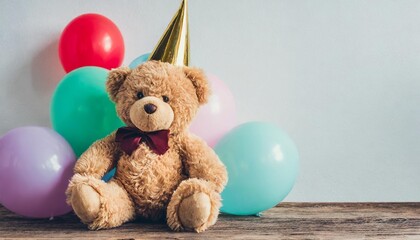 teddy bear in party hat sitting near balloons over white background