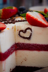 Close-up of a layered cake with vibrant red berry compote, chocolate heart decoration, and chocolate base, showcasing its texture and colors, ideal for sweet culinary themes.