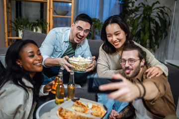 Multiracial group of friends taking selfie at pizza party.