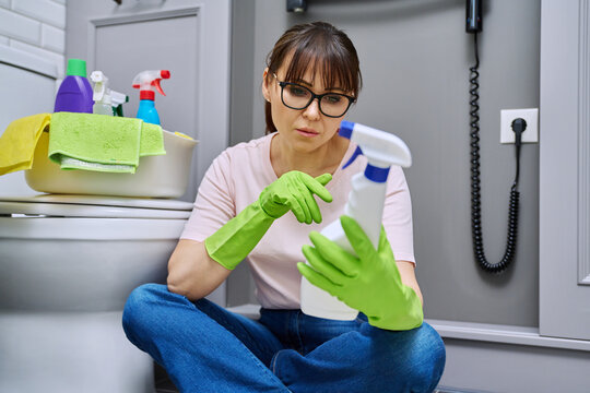 Woman reading label on spray cleaner, composition, instructions for use