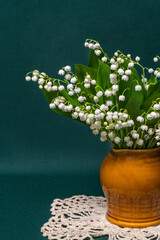a bouquet of white lilies of the valley in a vase on a green background. Delicate still life...
