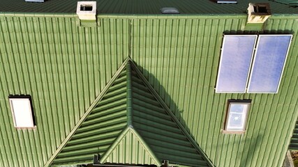 Pomarańczowy dach budynku kryty blachodachówka, okna dachowe, komin, widok z drona. - 741910244