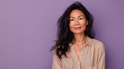 Mid aged Asian woman in beige blouse gracefully smiling to the camera isolated on lilac background with copy space,  women's day, stop Asian hate, Mother's Day.