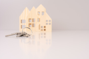 close-up house keys against the background of wooden house models. selective focus. investment, mortgage, real estate and real estate concept