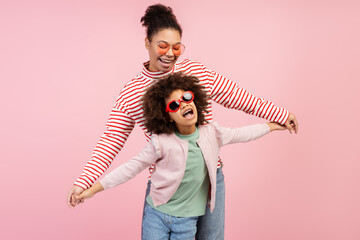 Portrait of smiling beautiful mother and little cute daughter wearing stylish sunglasses dancing