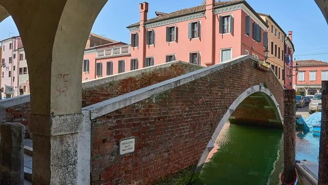 CHIOGGIA, ITALY - APRIL 19 2018: brick bridge Zitelle Vecchie over the Vena canal. Old buildings near the canal.