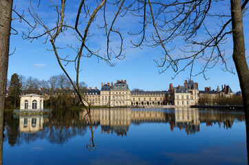 Beautiful Medieval landmark - royal hunting castle Fontainbleau with reflection in water of pond. - 741930635