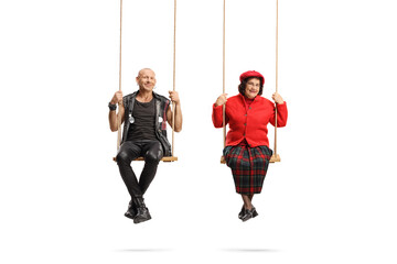 Punk and an elderly man sitting on swings and looking at camera