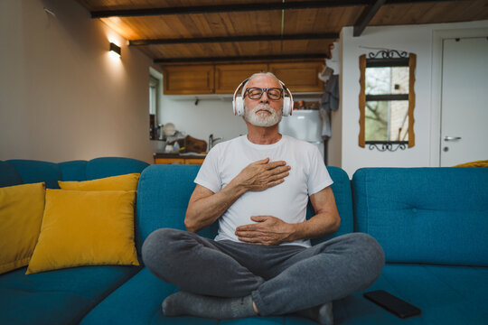 One senior man doing guided meditation yoga self care practice at home