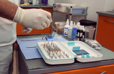 Doctor's hands in gloves picking up dental instruments