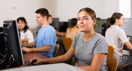 Positive female teacher working on computer in school class