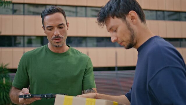 Cheerful postman delivering box to customer in modern business district closeup
