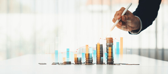 Coin stack with digital graphic indicator symbolizing business investment and economic growth. Businessman doing financial planning to achieve financial goal and contribute to profit. Shrewd