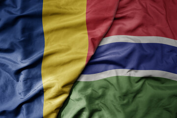 big waving national colorful flag of gambia and national flag of romania .