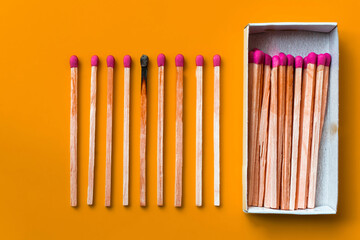 Success, defeat, achievement. The concept of happiness. Matches on a yellow background. Burnt dark match among normal matches. Burning match fire to its neighbors, a metaphor for ideas and inspiration - Powered by Adobe