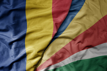 big waving national colorful flag of seychelles and national flag of romania .