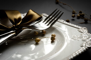 Romantic tabble setting with ribbon, plates, cutlery on black background. Empty plate. Mockup...