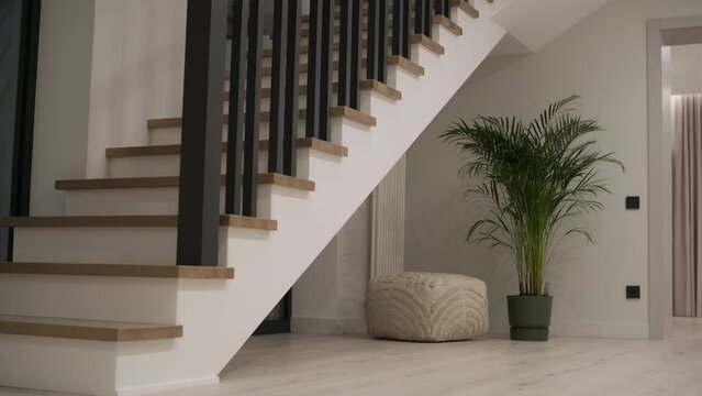 Interior design stylish wooden stairs inside the house with modern wooden railings and walls decorated with trendy lamps. Modern stairway or staircase inside in modern house interior