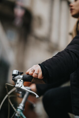 Close-up of woman's hands on bicycle handlebars in urban setting.