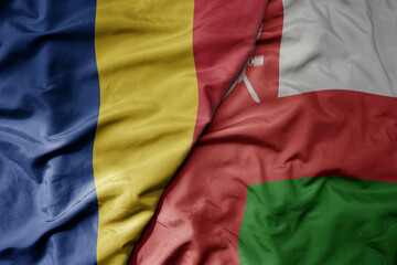 big waving national colorful flag of oman and national flag of romania .