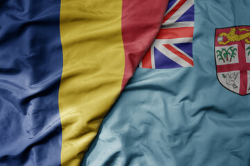big waving national colorful flag of Fiji and national flag of romania .