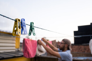 Man hanging clothes on terrace at sunset in sunny day 