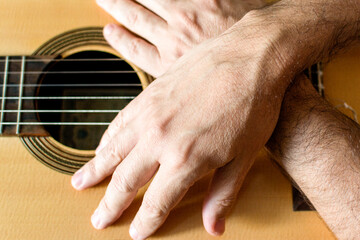 Hands of a classical guitarist on top of the guitar. Study of classical music.