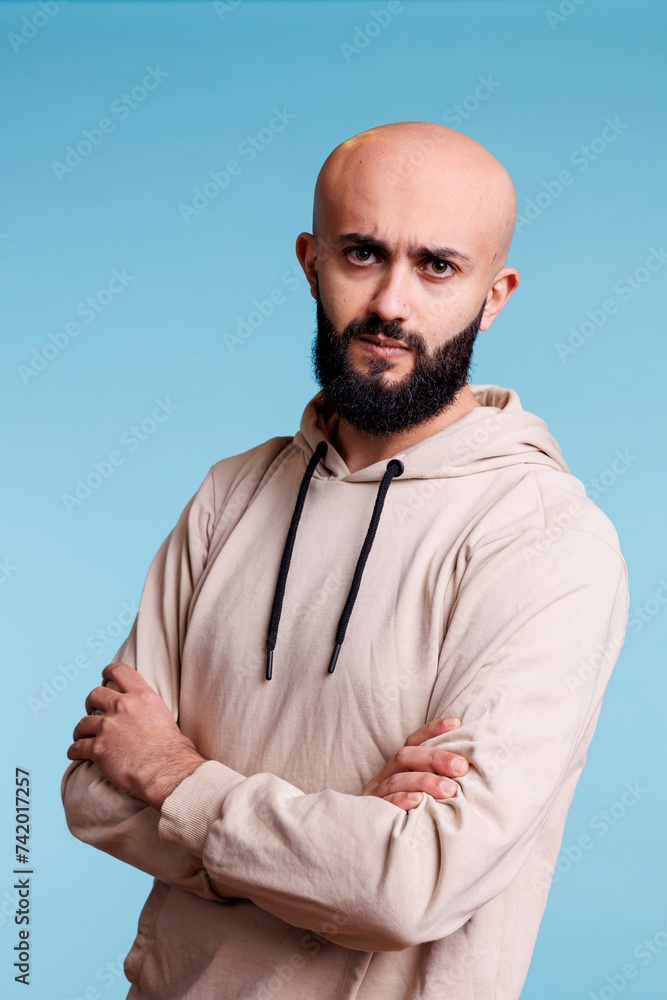 Poster serious arab man frowning eyebrows while posing with crossed arms studio portrait. confused person w