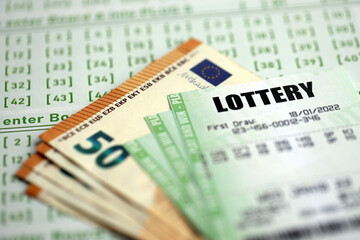 Green lottery tickets and euro money bills on blank with numbers for playing lottery close up