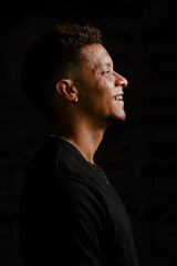 Low key portrait of young African man in profile smiling