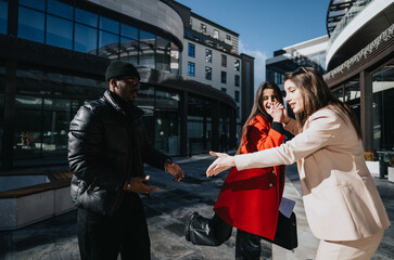 Two professional women sharing a laugh with a male colleague on a sunny day in a business district. The mood is light and friendly.