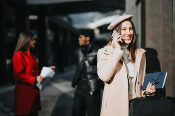 Casual businesswoman happily chatting on her mobile while walking on a sunny urban sidewalk, radiating positivity and confidence.