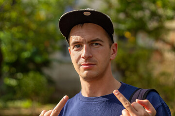 Obscene gesture. Young man in baseball cap and T-shirt shows the middle finger with both hands. Young man giving obscene gesture