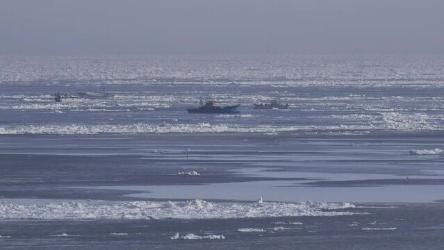 Hokkaido, Japan - February 19, 2024:  Fishing boats among drift ice at Nemuro strait in Hokkaido, Japan

