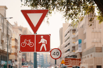 A red traffic sign in the neighbourhood features a bicycle and pedestrian symbol, promoting safety and shared use of the road infrastructure during daytime