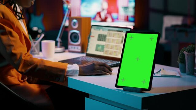 African american business student looking at isolated greenscreen, examining academic software spreadsheet to learn about tax services. Girl using tablet with blank copyspace layout. Camera A.